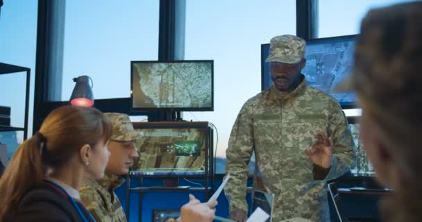 Afroamerikaner, männlicher Leiter des militärischen Hauptquartiers, im Gespräch mit Mitarbeitern der kaukasischen Armee, während sie Dokumente studieren und lesen. Militärische Ausbildung im Bürokonzept. — Stockvideo