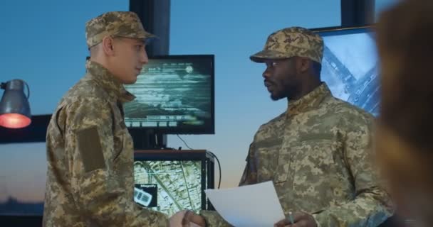 Soldados caucasianos e afro-americanos em uniformes se encontrando e cumprimentando com as mãos tremendo no escritório militar. Cabeças multiétnicas masculinas no exército conversando e discutindo algumas questões de operação . — Vídeo de Stock