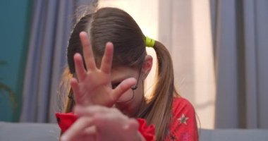 Gözlüklü, sevimli ve komik beyaz kızın oturma odasındaki kanepede kamera karşısında eğlenip dalga geçişini yakından çek. Evdeki kanepede oturan küçük çocuk otlanıyor..