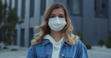 Maske takan ve şehre bakan kadın portresi. Sağlık ve güvenlik, N1H1 koronavirüs, virüs koruma ve tıbbi konsept. Sokakta koruyucu tıbbi maskeli genç bir kız.