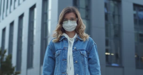 Een vrouw met een bril en een beschermend medisch masker met stopbord op straat. Gezondheid en veiligheid, N1H1 coronavirus, virusbescherming en medisch concept. Jong meisje met medisch masker buiten. — Stockvideo