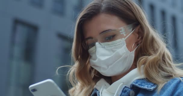 Close up mulher retrato vestindo óculos e máscara médica de proteção usando telefone inteligente na cidade. Saúde e segurança, coronavírus N1H1, cuidados de proteção contra vírus e conceito médico . — Vídeo de Stock