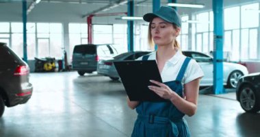 İndirimde olan arabalarla koridorda duran ve klasördeki evrakları dolduran biçimsiz güzel beyaz kadın araba tamircisi. Garajda gülümseyen mutlu kızın portresi. Otomobil satışı kavramı.