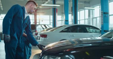 Beyaz adam, araba tamirhanesinde üniformalı genç bir kıza araba tamir etmeyi öğretiyor. Erkek meslektaşı büyük garajda motoru tamir ederken ve işlemleri anlatırken kadın işçi öğreniyor..