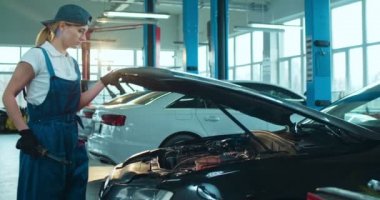 Otomobil tamircisinin beyaz kadın çalışanı. Garajdaki el feneriyle arabaya giriyor ve arama yapıyor. Otomobil tamir eden kadın mühendis.