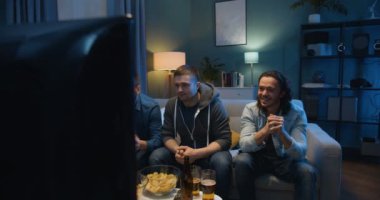 Erkek futbol fanatikleri TV ekranının önünde kanepede oturup geceleri bira ve atıştırmalıklarla favori takım için tezahürat yapıyorlar. Erkekler maçta kazanır ve akşamları birlikte vakit geçirirken sarılırlar..