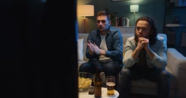 Akşamları oturma odasında kanepede oturan ve televizyondaki futbol maçında gol anı izleyen üç beyaz erkek arkadaş. Üzgün ve hayal kırıklığına uğramış adamlar kayıp bir gol için endişeleniyorlar ya da kaybediyorlar..