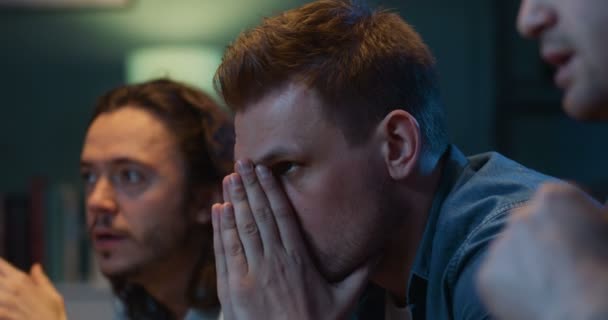 Gros plan de beaux hommes blancs fans de football assis sur le canapé et regarder le match de football tard dans la nuit. Les gars applaudissant et inquiétant pour l'équipe préférée qui manque but et perdre dans le jeu .