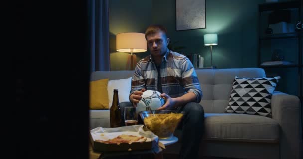 Hombre caucásico viendo deporte juego en la televisión en casa por la noche. Tipo decepcionado preocupándose porque su equipo favorito falta gol o perder partido. Fútbol fan viendo canal deportivo . — Vídeo de stock