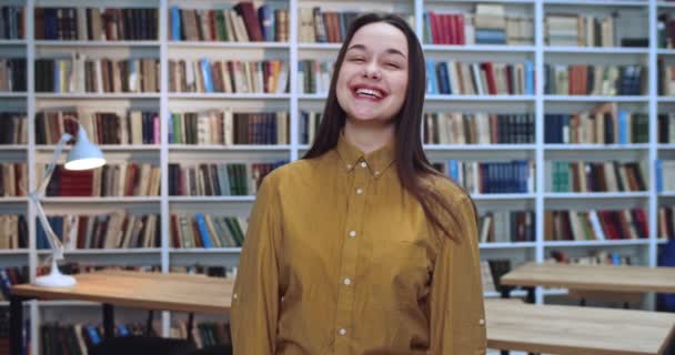 Portret di studente felice con sorprendente sorriso raccogliendo informazioni da diversi libri in biblioteca . — Video Stock
