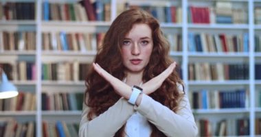 Güzel, korkmuş kızıl saçlı bir kızın portresi kütüphanede karşıdan karşıya geçip hayır diyor. Arka planda kitaplık..