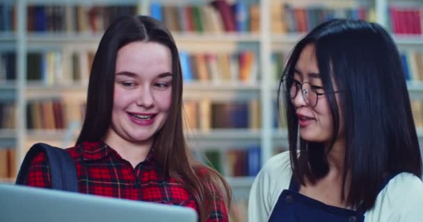 Close-up portret inteligentny azjatycki student w okularach słuchając jej kolega z klasy w bibliotece. — Wideo stockowe