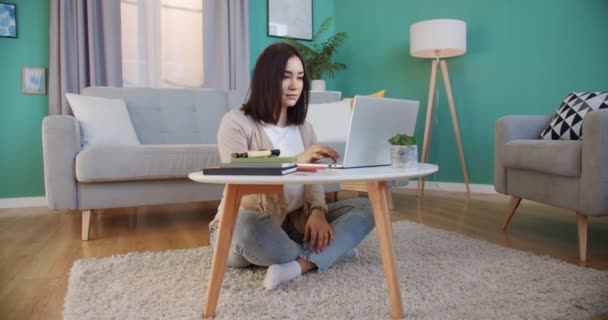 Joven estudiante preocupada trabajando en el ordenador portátil, estudiar en línea con el profesor de Internet, la resolución de problemas en casa. Mujer seria buscar inspiración e ideas. Escribir notas, concepto de enseñanza — Vídeos de Stock