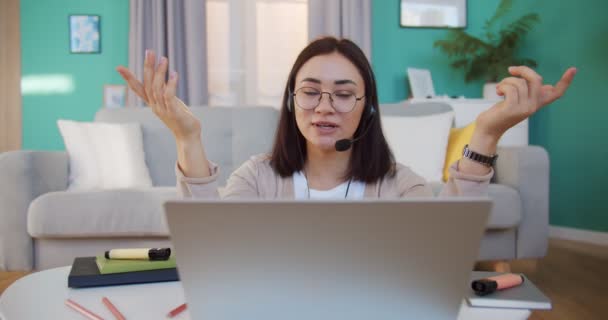 Mujer asistente de negocios lleva auriculares video llamadas cliente distante en el ordenador portátil. Consultor que habla con el cliente usando la aplicación de computadora de chat virtual . — Vídeos de Stock