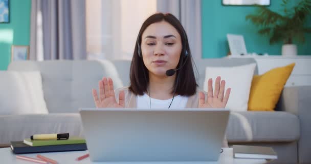 Mujer feliz en auriculares hablando por webcam en el entrenamiento de webinar, mirando a la computadora portátil, tomando notas, estudiante niña hablando por videollamada, enseñanza en línea, cliente de consultoría, concepto de e-coaching — Vídeo de stock