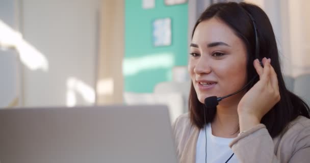 Mujer de negocios hablando con auriculares sentada en casa. Chica en auriculares hablando con el cliente, haciendo videollamada, mirando a la computadora portátil, escribiendo notas, hablando por webcam . — Vídeos de Stock