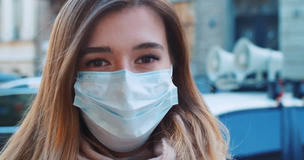 Gros plan portrait d'une belle femme en bonne santé portant un masque de protection à côté d'une voiture de police haut-parleur et regardant la caméra. Concept de vie en santé et sécurité, coronavirus, protection contre les virus, pandémie — Video