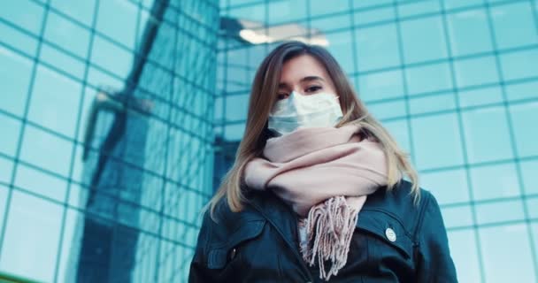 Ritratto di una dolce bella ragazza che indossa una maschera protettiva sulla strada guardando il cielo e che alla macchina fotografica. Concetto di salute e sicurezza vita, coronavirus, protezione del virus . — Video Stock