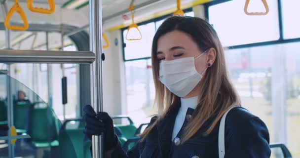 Detailní portrét mladé blondýny s maskou na obličeji jezdí v tramvaji, drží zábradlí, chrání před infekcí coronavirus covid-19 ve veřejné dopravě. Zdraví a bezpečnost, karanténa — Stock video