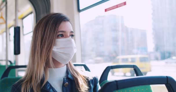 Potret mahasiswa muda bertopeng medis duduk di bus dalam perjalanan ke universitas dan melihat melalui jendela di jalan-jalan kosong. Menerima kesehatan dan keamanan, karantina coronavirus, perlindungan virus — Stok Video