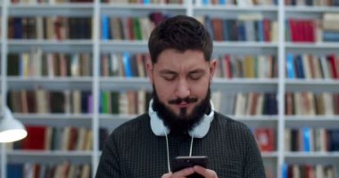 Genç beyaz erkek kütüphane çalışanı ya da kulaklık takıp cep telefonundan mesaj atan. Adam İncil 'de akıllı telefondan yazıp kaydırıyor. Kitap mağazası kozmozcusu mesajlarla sohbet ediyor.