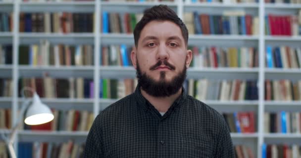 Close-up van Kaukasische jongeman met baard die vrolijk lacht en OK-gebaar toont met de hand in de bibliotheekkamer. Gelukkige mannelijke student of leraar die gelukkig is na de examens. Succes in studie of onderzoek. — Stockvideo