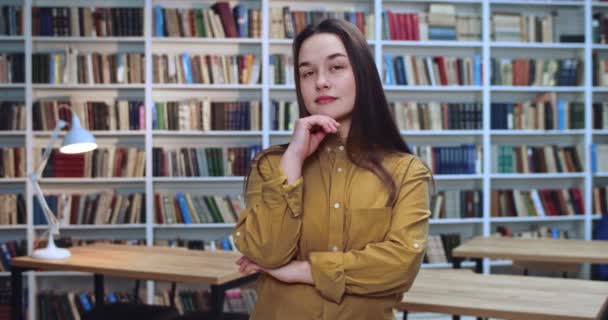 Retrato de estudante morena atenciosa com longo cabelo blach awesom pensando na biblioteca . — Vídeo de Stock