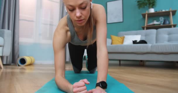 Närbild porträtt av ung vacker kvinna kommer att träna yoga och vistas i planka, rulla ut blå träningsmatta i slow motion. Sport och fitness. Träning, träning och wellness koncept. — Stockvideo