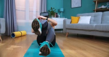 Yoga minderinde oturup spor yaparken sanal gerçeklik gözlüğü takan beyaz bir kadın. Formda kadın antrenmanı, kas egzersizleri evde bacakları esnetme egzersizleri, ön görüş..