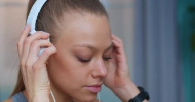 Formda kız portresi yoğun spor egzersizlerinden sonra evde oturup meditasyon dinledikten sonra egzersiz sonrası kulaklıklarda müzik dinlemek. Spor ve spor. Eğitim, egzersiz, sağlık konsepti.