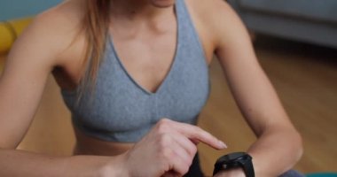 Güzel, modern oturma odasında çalıştıktan sonra yeni akıllı saatini deneyen genç bir kadının yakın portresi. Spor ve spor. Eğitim, egzersiz ve sağlık konsepti.