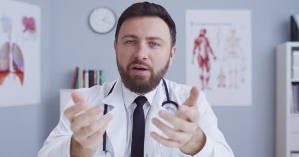 Fešák běloch lékař blogger v bílém plášti v klinice poradenství o zdravotní péči on-line. Muž, nemocniční pracovník má profesionální lékařskou konzultaci na internetu během qurantine. — Stock video