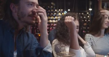 Beyaz erkek ve kadın arkadaşlar barda televizyon kanalında spor maçı izliyorlar. Kızlar takımlarının golünü ya da galibiyetini kutlarken erkekler üzgün ve hayal kırıklığına uğruyor.