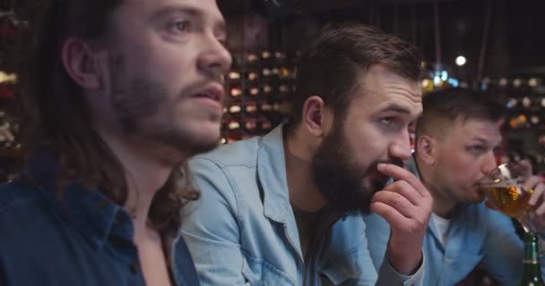 Amis masculins caucasiens remonter le moral dans le bar en regardant le jeu de sport. Les hommes crient et rient comme but de l'équipe au pub. Les fans de football regarder match à la télévision avec de la bière . — Video