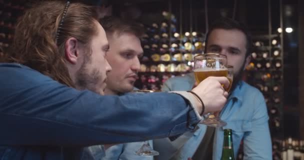 Blanke mannelijke vrienden juichen op in de bar tijdens het kijken naar sport wedstrijd. Knappe mannen die juichen met een glas bier in de kroeg. Voetbalfans kijken wedstrijd op tv en drinken. — Stockvideo