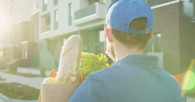 Teslimat servisinden yemek getiren adamın dikiz aynasından. Sokakta yürüyen kuryenin arka görüntüsü. Karantina sırasında erkek marketi kapı kapı dolaşıp teslimat yapıyor. Ürünleri çevrimiçi sipariş