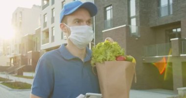 Mavi şapkalı bir kurye elinde yemek paketi, dinleme, akıllı telefondan mesaj gönderme adresi arıyor. Adam karantina sırasında marketten eve, kapı kapı teslimat yapıyor..