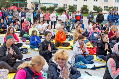 Rusya, Vladivostok, 06/18/2016. Birçok seyirci yere otur ve yoga asana (duruş) Yoga eğitim açın. Spor ve sağlık. Hint yoga.