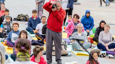 Rusya, Vladivostok, 06/18/2016. Fotoğrafçı alır fotoğraf Yoga eğitim açın. Birçok seyirci yoga eğitim etrafında onu vardır. Hobi ve açık olaylar. Hint yoga.