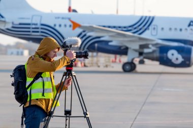 Rusya, Vladivostok, 10/13/2017. Kameraman uçak pist üzerinde video vuruyor. Aurora Hava Yolları'nın Airbus A319 arka plan üzerinde. Lekelenme, hobi, Havacılık Uçak.