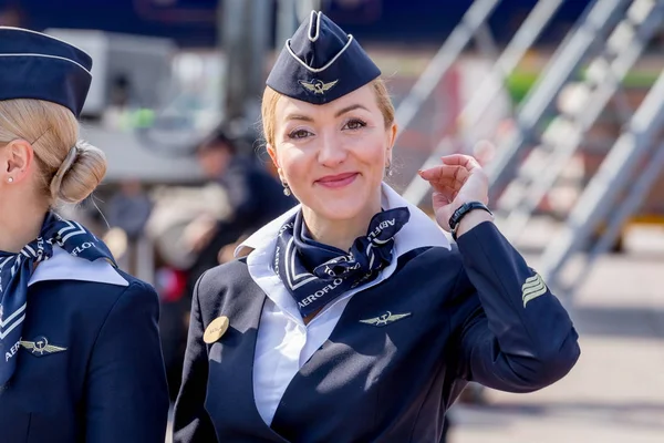 Rusya, Vladivostok, 10/13/2017. Güzel hostes Aeroflot Havayolları havaalanı üzerinde resmi koyu mavi üniforma giymiş. Arka plan üzerinde yolcu jet uçağı. Uçağının mürettebatı. Havacılık ve ulaşım.