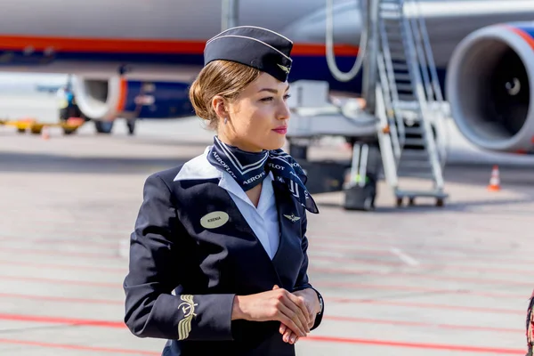 Rusya, Vladivostok, 10/13/2017. Güzel hostes Aeroflot Havayolları havaalanı üzerinde resmi koyu mavi üniforma giymiş. Arka plan üzerinde yolcu jet uçağı. Uçağının mürettebatı. Havacılık ve ulaşım.