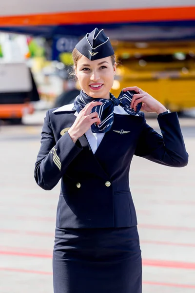Rusya, Vladivostok, 10/13/2017. Güzel hostes Aeroflot Havayolları havaalanı üzerinde resmi koyu mavi üniforma giymiş. Arka plan üzerinde yolcu jet uçağı. Uçağının mürettebatı. Havacılık ve ulaşım.