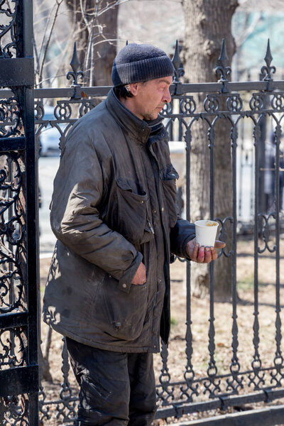 Russia, Vladivostok, 04/08/2018. Dirty poor man begging alms in the street. Poverty and poor people. Beggars on the streets of the city. Social problems concept.