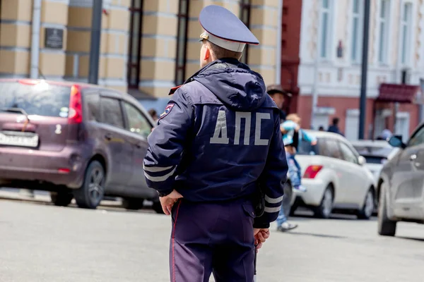 Bir polis şehir merkezindeki yürüyen insanlar izliyor. 