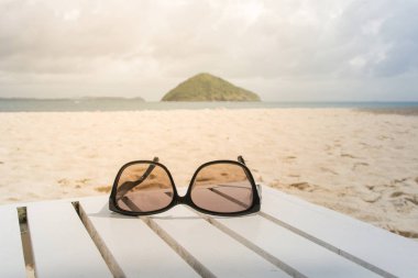 Siyah güneş gözlüğü olduğunu plaj arka plan ve güneşli ışık Beyaz ahşap masa yüzünde sabah
