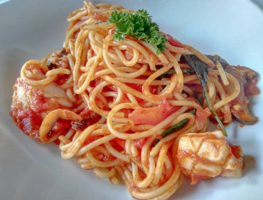 Plaka üzerinde domates soslu deniz mahsulleri spagetti