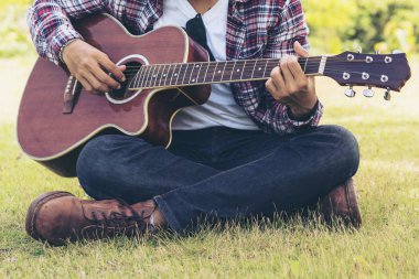 Adamın elini yeşil çimlere oturup gitar çalmak