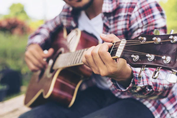 La mano del hombre tocando la guitarra, sentado en la hierba verde —  Fotos de Stock