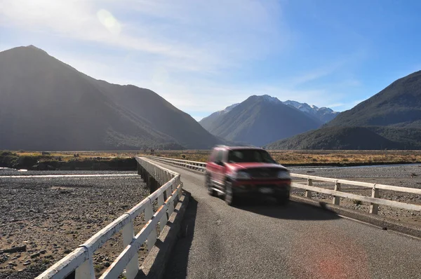 Car driving across single-lane bridge in New Zealand